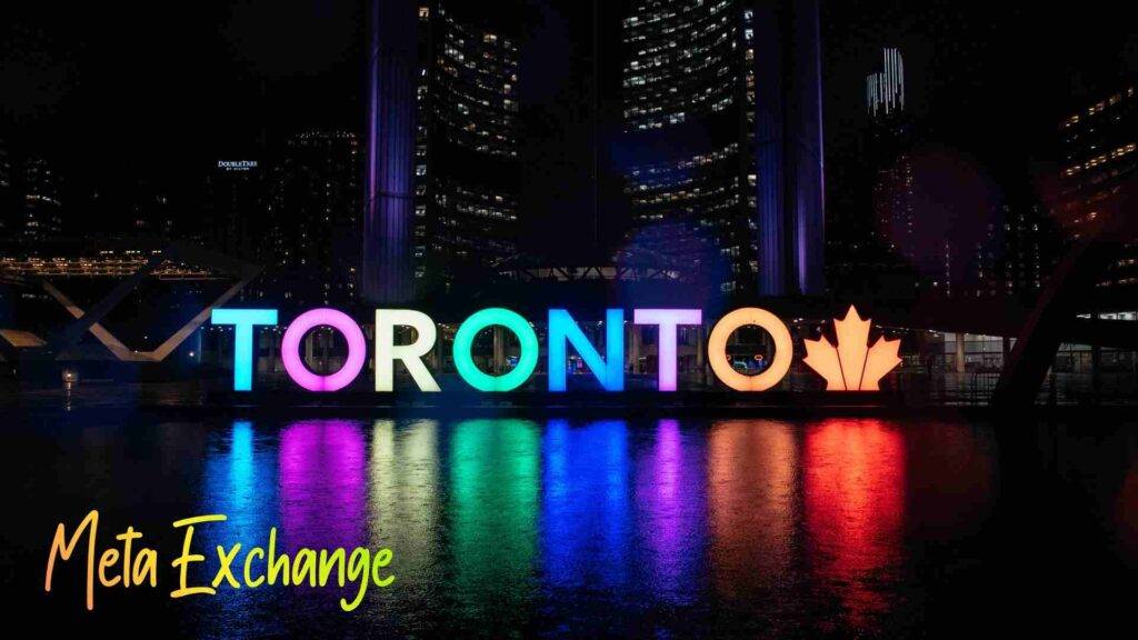 Colorful TORONTO sign reflecting over water at night — symbolizing Meta Exchange Toronto’s vibrant and global money transfer network.